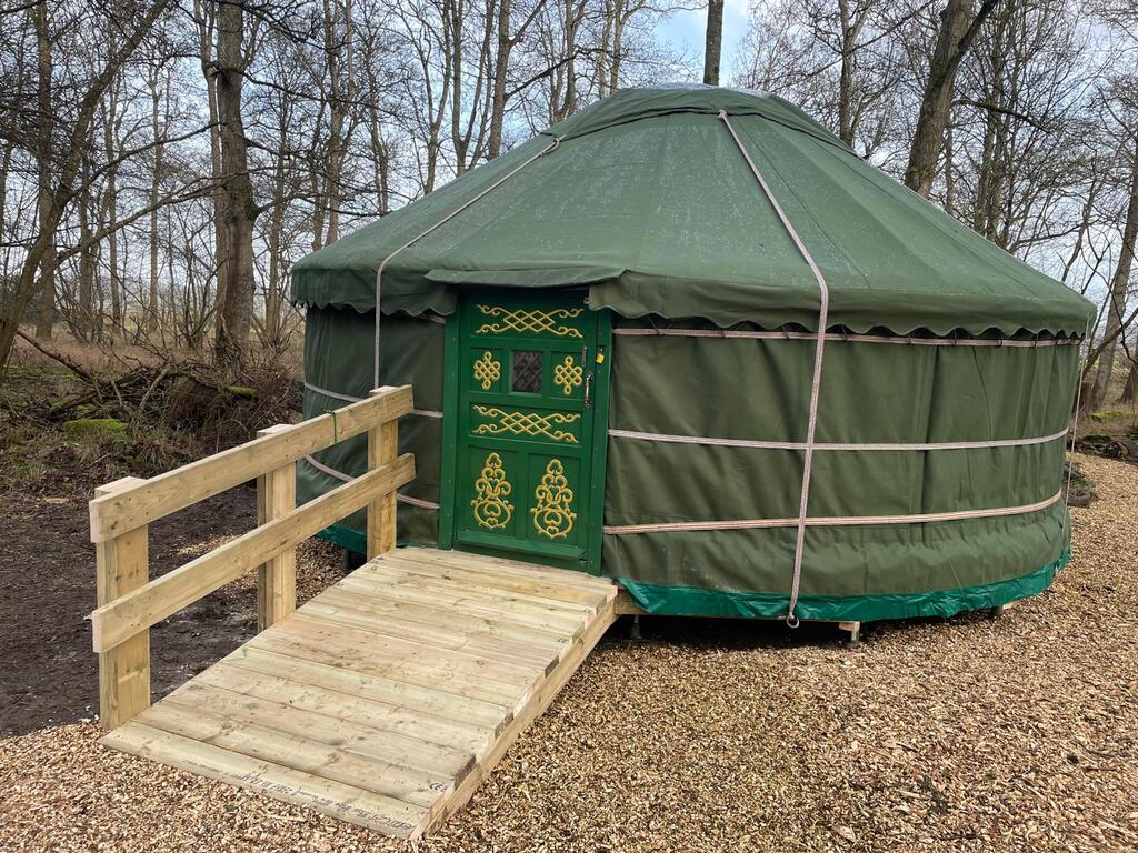 Green forest school yurt with wooden wheelchair access ramp at Little Wild Things woodland site
