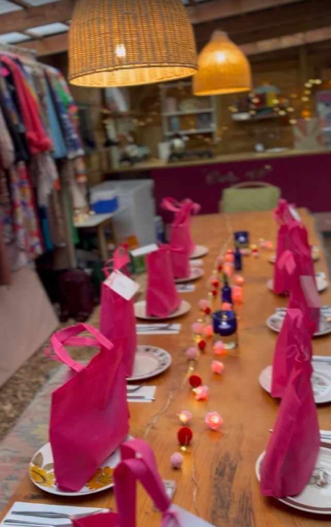 A long wooden dining table set with pink napkins and candles inside a yurt