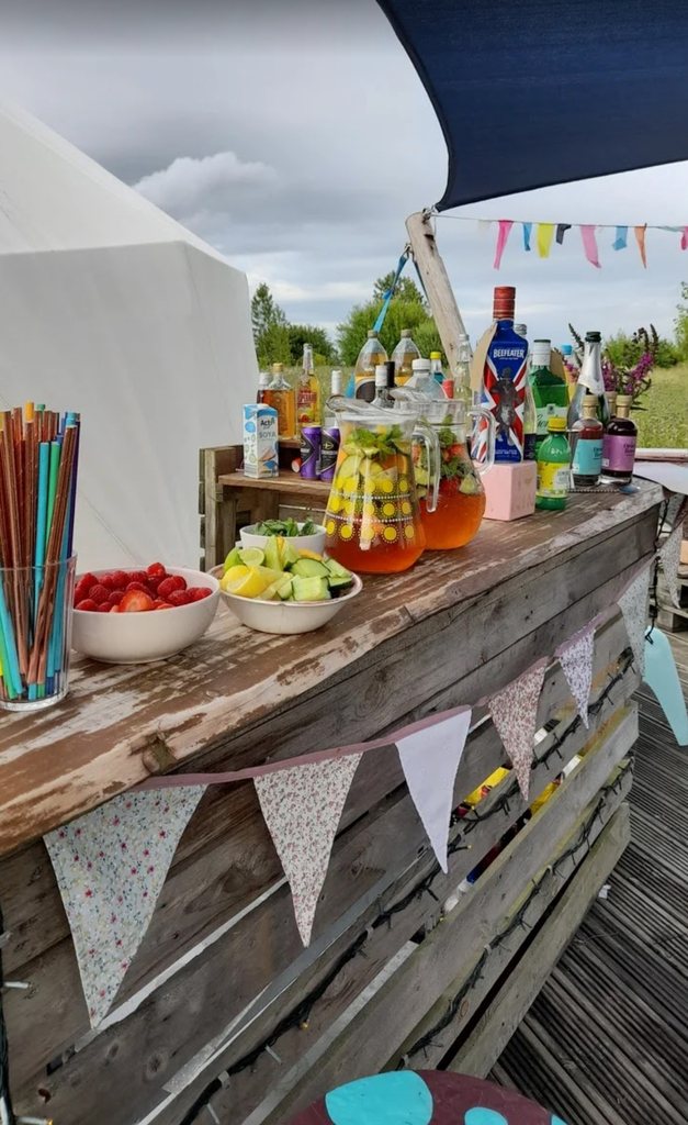 An outdoor wooden bar decorated wth bunting and fresh fruit bowls.