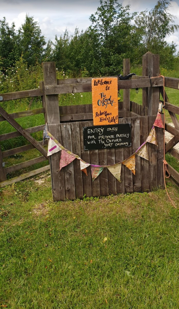 A rustic wooden gate decorated with colourful bunting and a welcome sign.