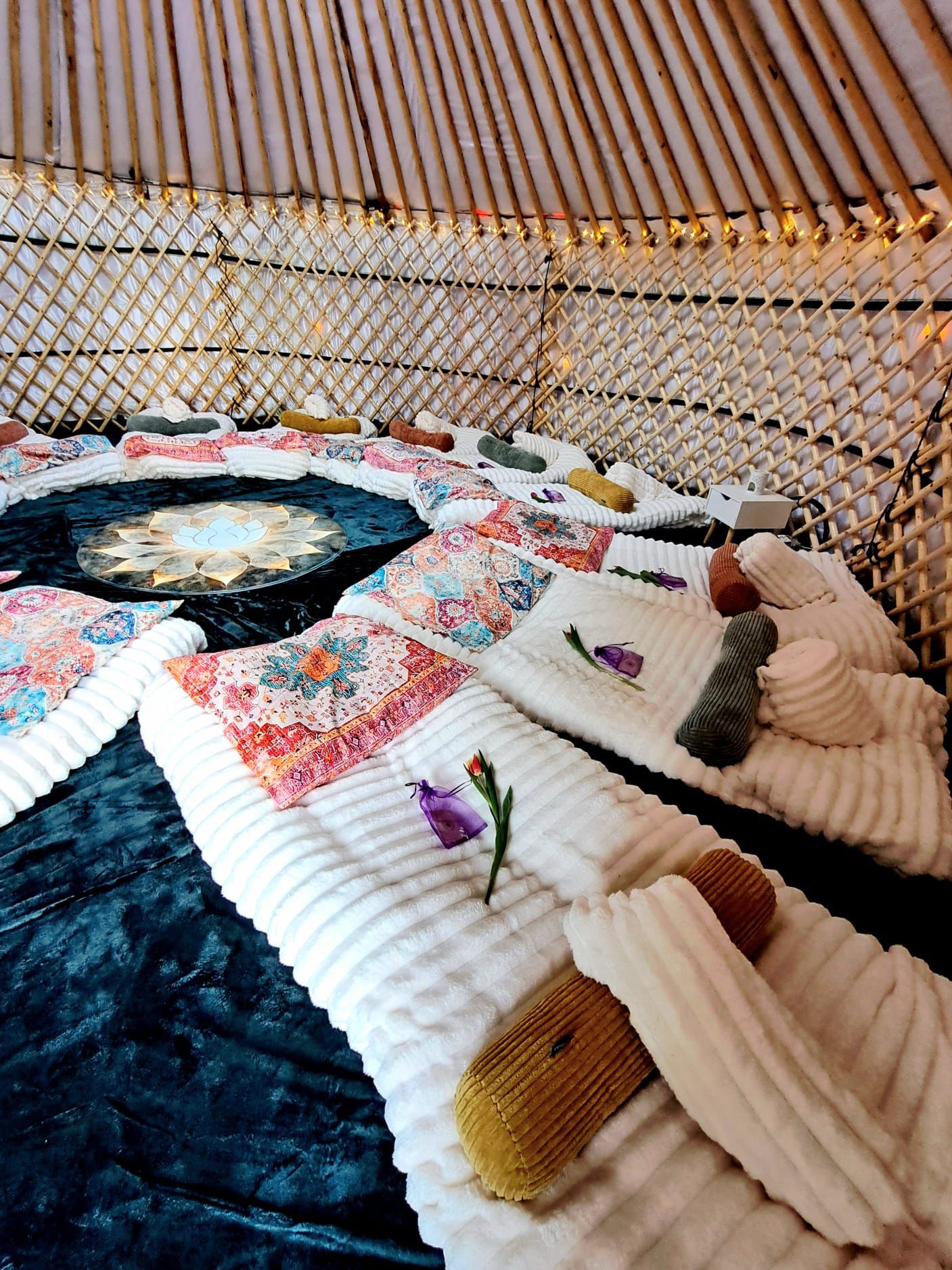 Interior of a cozy yurt feathering colourful bohemian bedding, wooden lattices walls, and a warm atmosphere