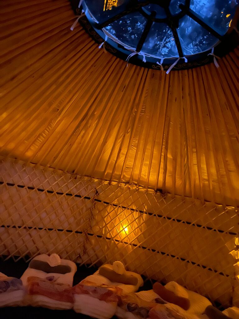 Yurt Skylight ambient lighting - Visit our Oxford Show yurt or Speak to Us Nighttime view of a yurt interior showing the glowing wooden roof poles and warm ambient lighting